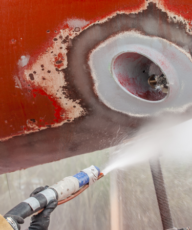 worker-sandblasting-the-corroded-hull-of-a-boat-2023-11-27-05-23-47-utc